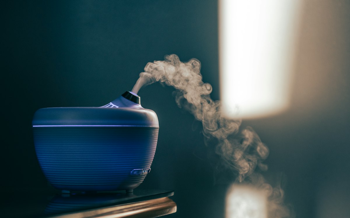 Blue humidifier releasing mist in a dim room