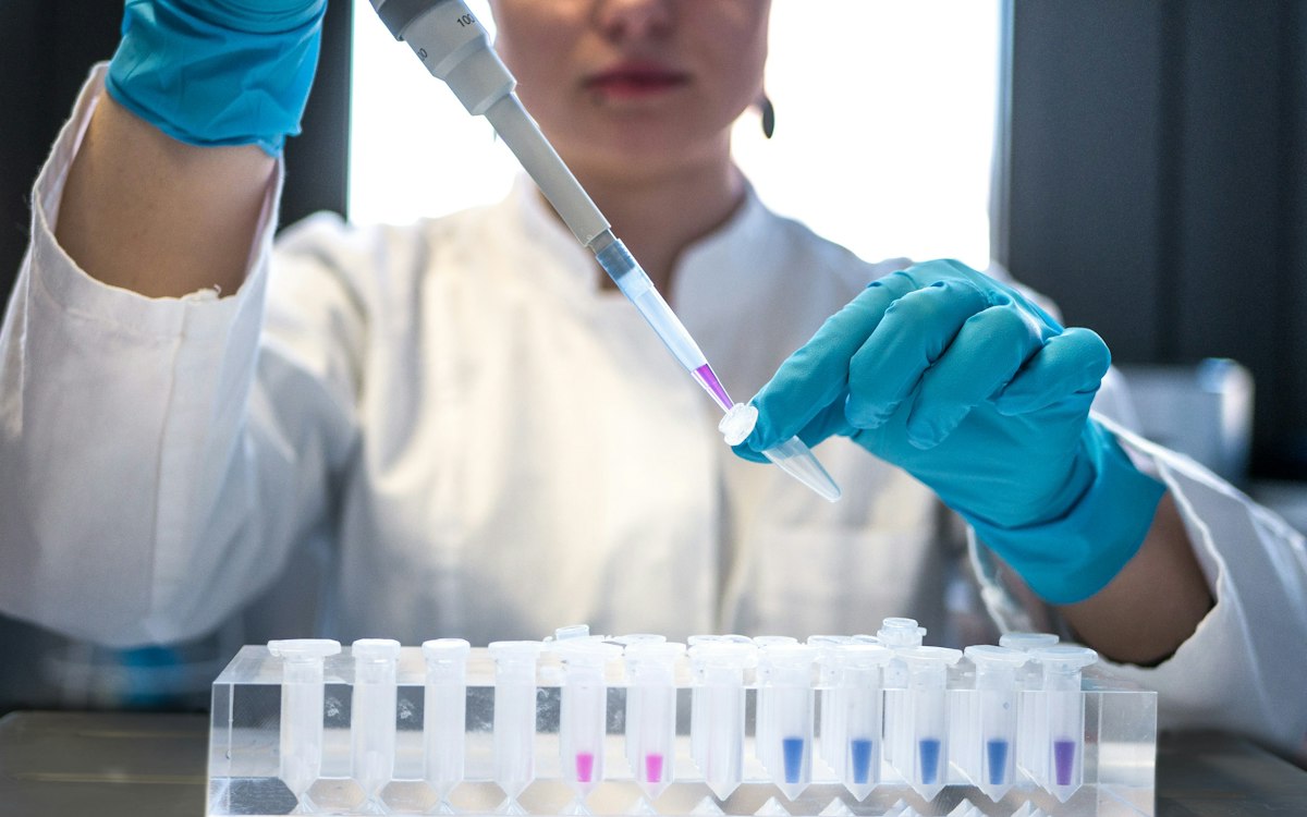 Researcher in gloves pipetting samples in a lab
