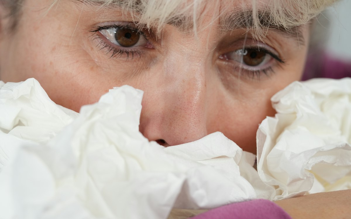 Person holding tissues up to their nose